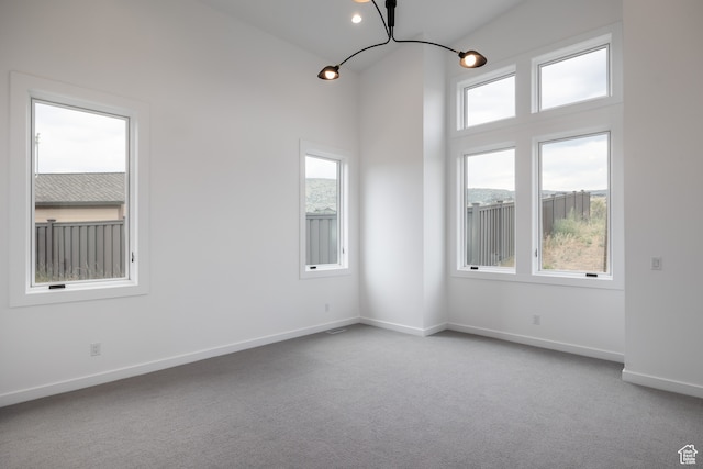 carpeted spare room with a notable chandelier and a healthy amount of sunlight