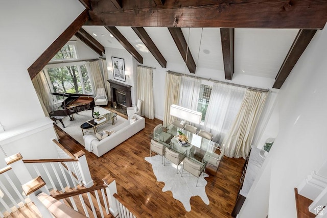 living area featuring a fireplace, high vaulted ceiling, wood finished floors, and beam ceiling