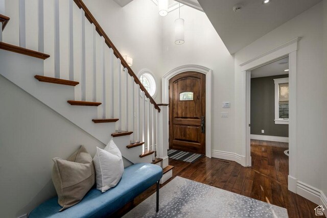 entryway with baseboards, a towering ceiling, stairway, and wood-type flooring