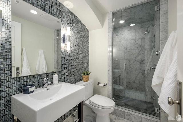 bathroom with a shower stall, marble finish floor, toilet, vanity, and backsplash