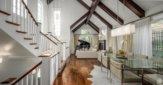 dining space with wood-type flooring, high vaulted ceiling, beamed ceiling, and stairs