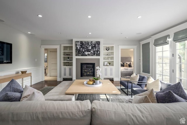 living area with built in features, recessed lighting, and dark wood finished floors