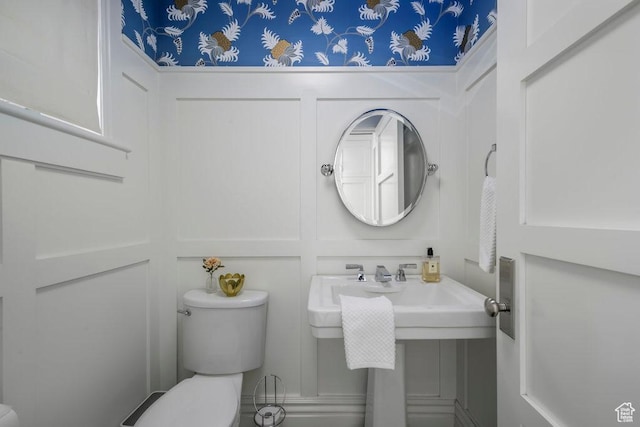 half bath with toilet and a decorative wall
