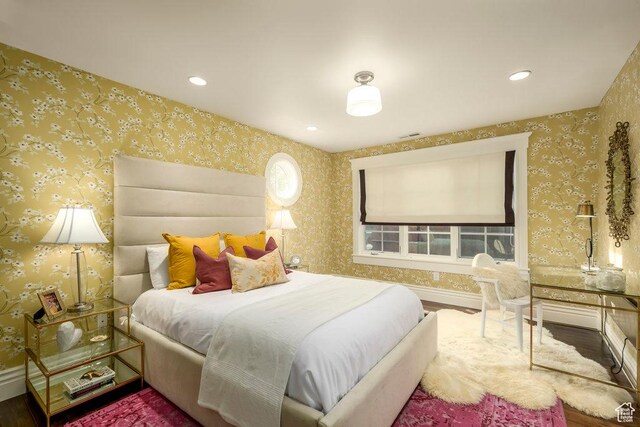 bedroom featuring baseboards, wallpapered walls, and wood finished floors