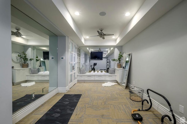 hall featuring baseboards, a tray ceiling, and recessed lighting