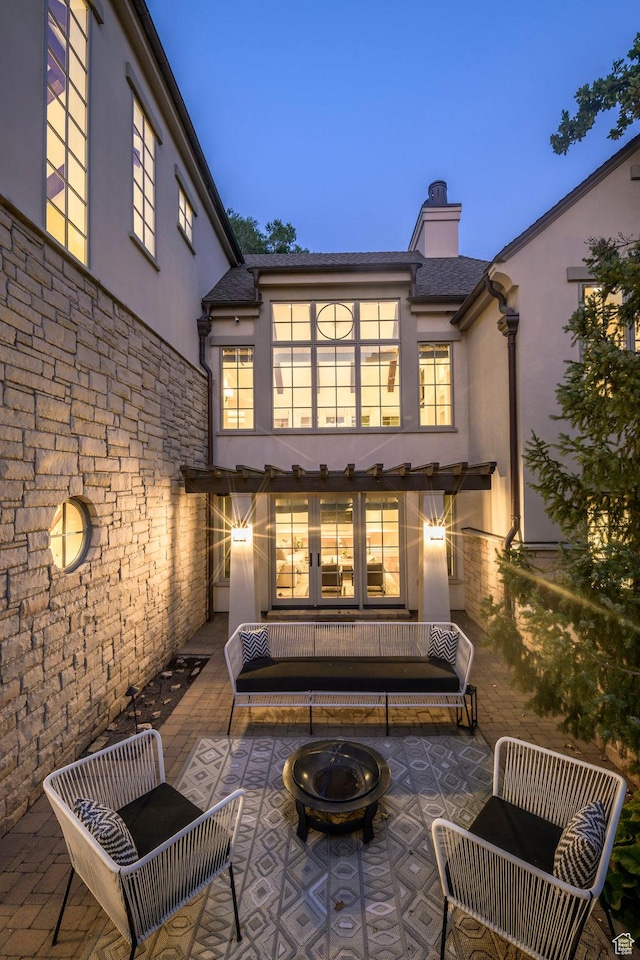 back of property featuring a chimney, a fire pit, stucco siding, and a patio area