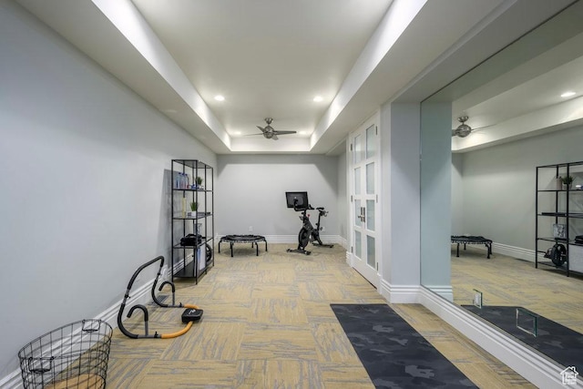 exercise room featuring a tray ceiling, baseboards, recessed lighting, and a ceiling fan