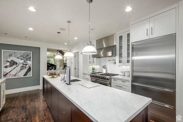 kitchen featuring a sink, glass insert cabinets, wall chimney range hood, and high end appliances