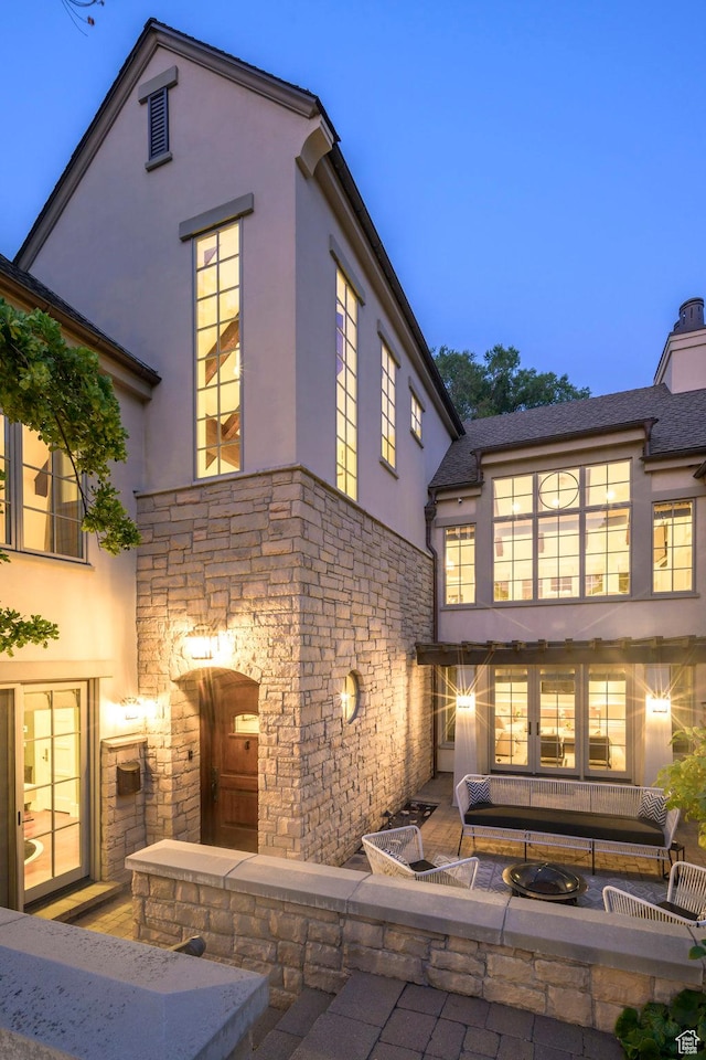 rear view of property featuring stucco siding, a patio area, and stone siding