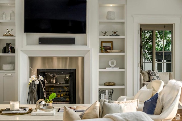 living area with a fireplace, wine cooler, and built in features
