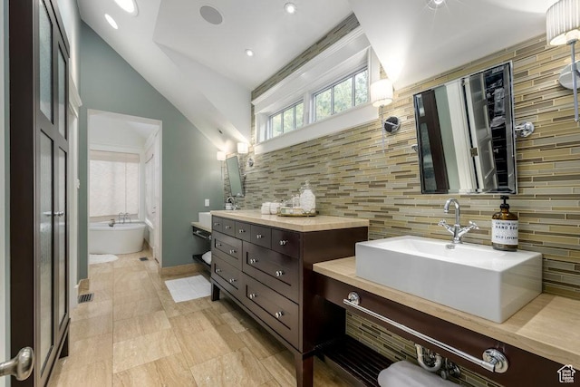 full bath featuring a sink, vaulted ceiling, backsplash, and a freestanding bath