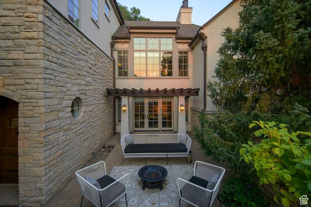 back of property with a fire pit, a patio area, french doors, a chimney, and stucco siding