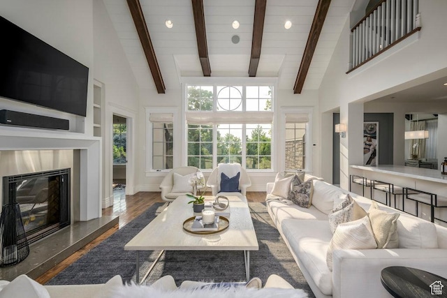 living area with baseboards, high vaulted ceiling, a high end fireplace, and wood finished floors