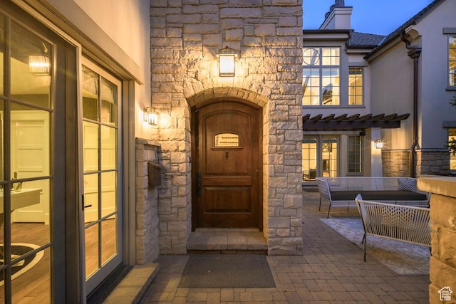 view of exterior entry with stone siding, a chimney, and an outdoor living space