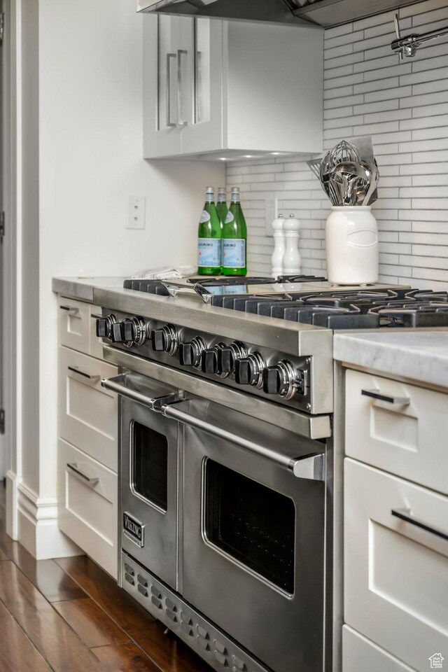 kitchen featuring white cabinetry, range with two ovens, and decorative backsplash
