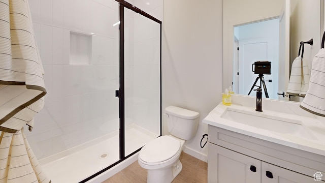 bathroom featuring toilet, a stall shower, and vanity
