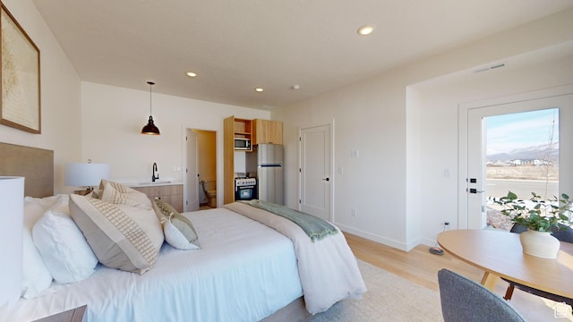 bedroom with baseboards, a sink, freestanding refrigerator, recessed lighting, and light wood finished floors