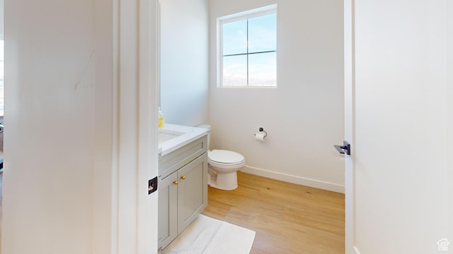 bathroom with toilet, wood finished floors, vanity, and baseboards