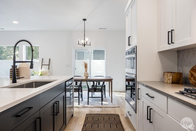 608 E Simpson Ave S, Salt Lake City, UT 84106 - kitchen featuring a notable chandelier, light wood-style flooring, white cabinets, a sink, and dishwashing machine
