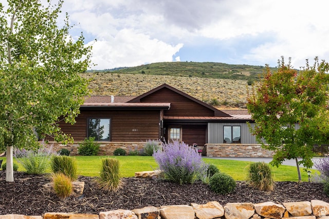 log cabin with board and batten siding, an attached garage, stone siding, and a front yard