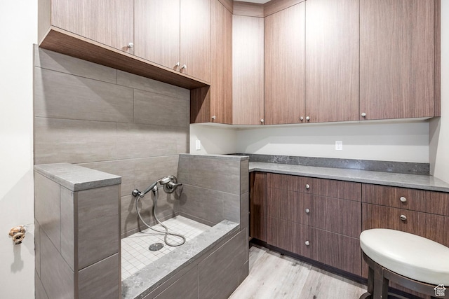 bathroom with a tile shower and wood finished floors