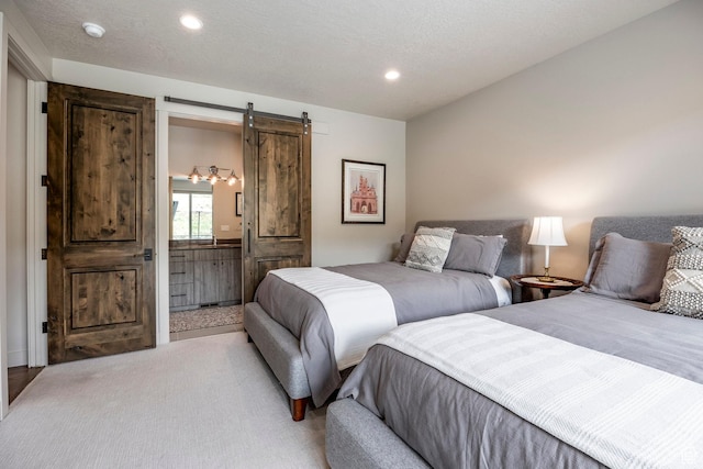 bedroom with ensuite bath, recessed lighting, and a barn door