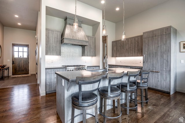 kitchen with a kitchen breakfast bar, a kitchen island with sink, modern cabinets, range, and custom range hood
