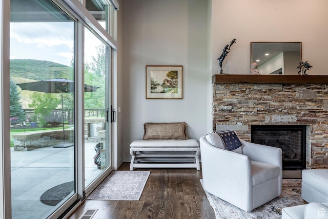 living area featuring visible vents, a stone fireplace, wood finished floors, and a high ceiling