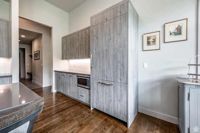 kitchen featuring modern cabinets, stainless steel microwave, and baseboards
