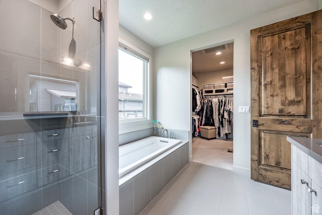 full bath featuring tile patterned floors, a garden tub, a spacious closet, and a stall shower