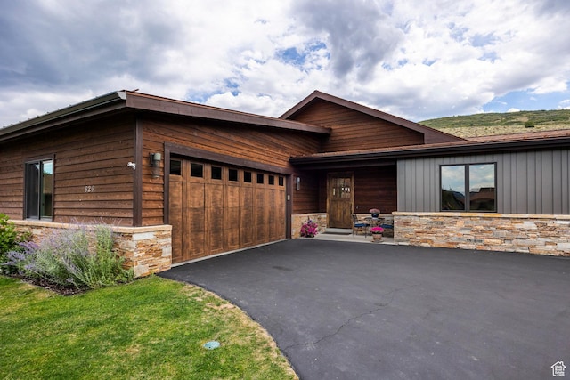 rustic home with a garage, driveway, and stone siding