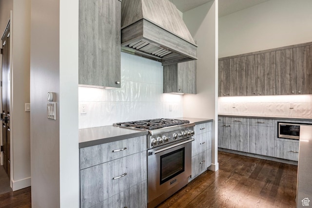 kitchen with dark wood finished floors, high end stove, modern cabinets, decorative backsplash, and premium range hood