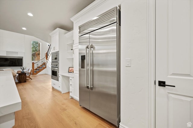 kitchen featuring light countertops, light wood finished floors, recessed lighting, white cabinetry, and built in appliances