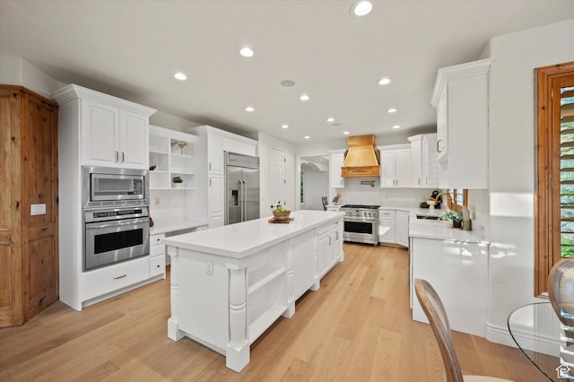 kitchen with open shelves, a center island, a sink, built in appliances, and custom exhaust hood