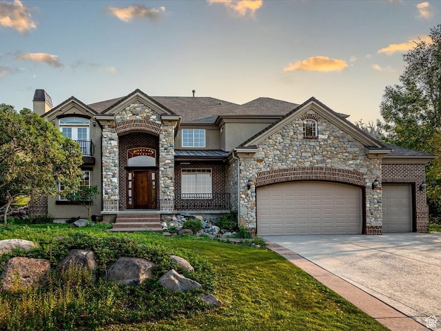 french country style house with stone siding, stucco siding, driveway, and a garage
