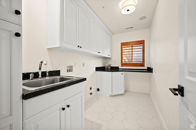washroom with gas dryer hookup, hookup for a washing machine, baseboards, a sink, and cabinet space