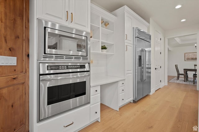 kitchen with light countertops, white cabinetry, open shelves, light wood-type flooring, and built in appliances