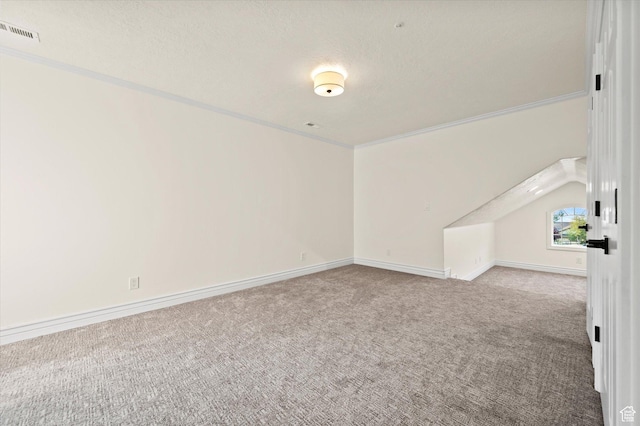 empty room featuring carpet flooring, a textured ceiling, baseboards, visible vents, and ornamental molding