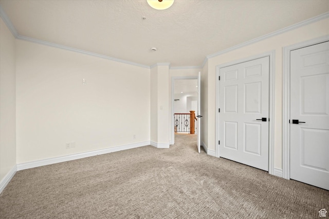 unfurnished bedroom featuring baseboards, a textured ceiling, crown molding, and light colored carpet