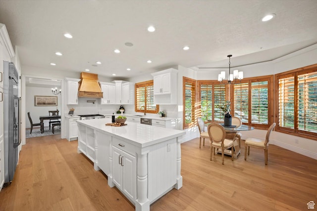 kitchen featuring white cabinetry, light countertops, a chandelier, light wood-style flooring, and custom exhaust hood
