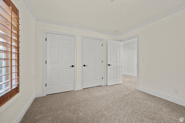unfurnished bedroom with baseboards, ornamental molding, and carpet
