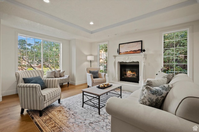 living room with a premium fireplace, recessed lighting, ornamental molding, baseboards, and wood finished floors