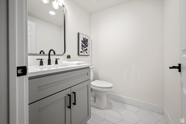 half bath featuring baseboards, toilet, tile patterned flooring, and vanity