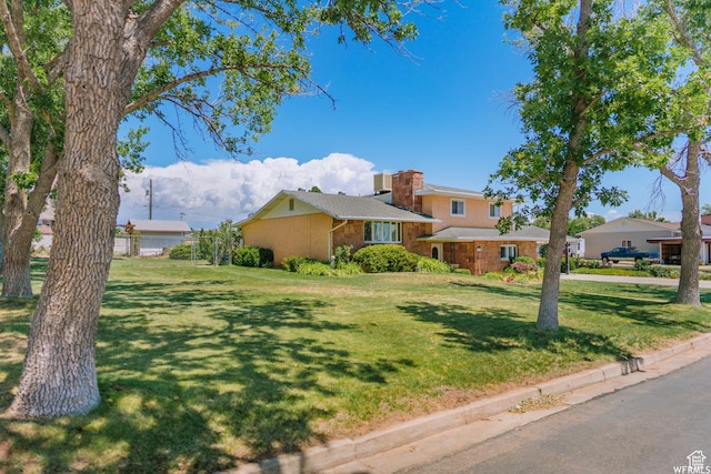 view of front of house with brick siding, a chimney, and a front yard