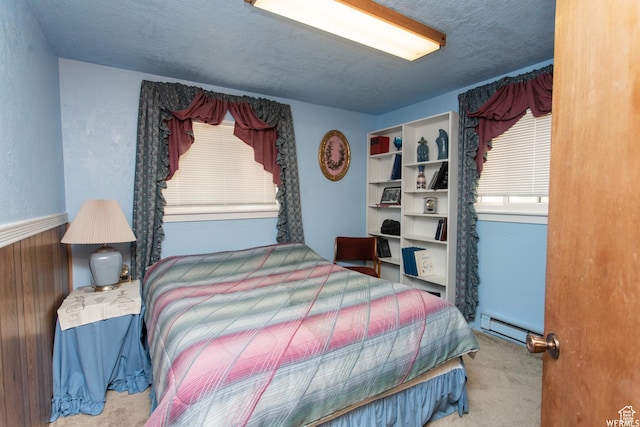 carpeted bedroom featuring baseboard heating and a textured ceiling