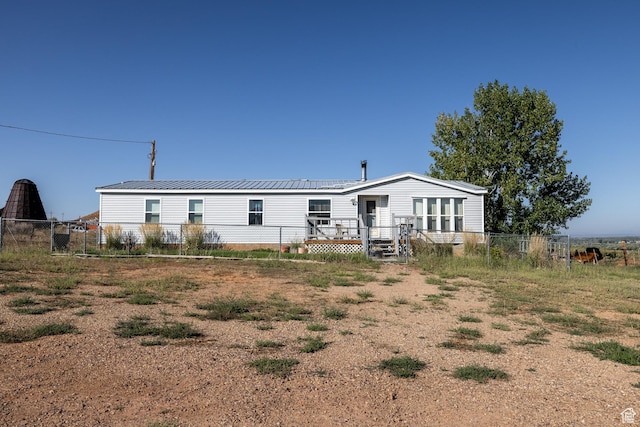 rear view of house featuring metal roof and fence
