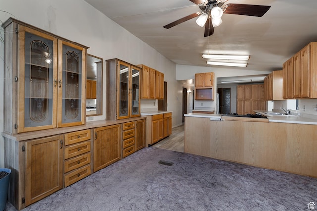 kitchen with light countertops, light colored carpet, glass insert cabinets, vaulted ceiling, and a peninsula