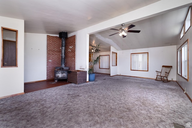 unfurnished living room featuring lofted ceiling with beams, carpet floors, a wood stove, and a healthy amount of sunlight