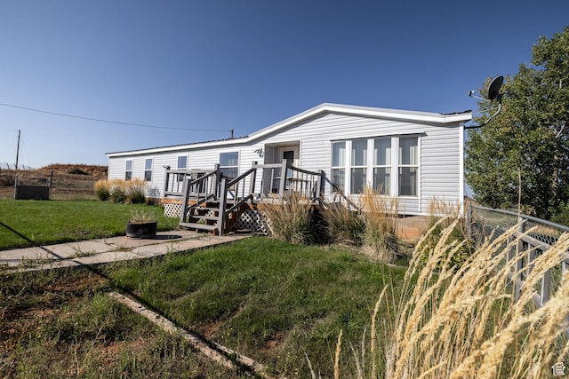 view of front of home featuring a front lawn, fence, and a wooden deck