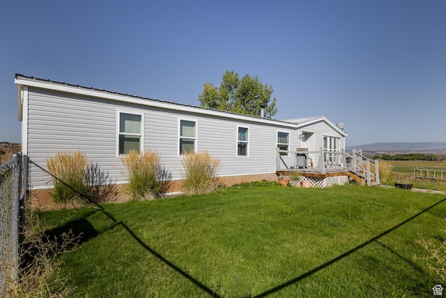 back of house featuring a yard, metal roof, fence, and a wooden deck